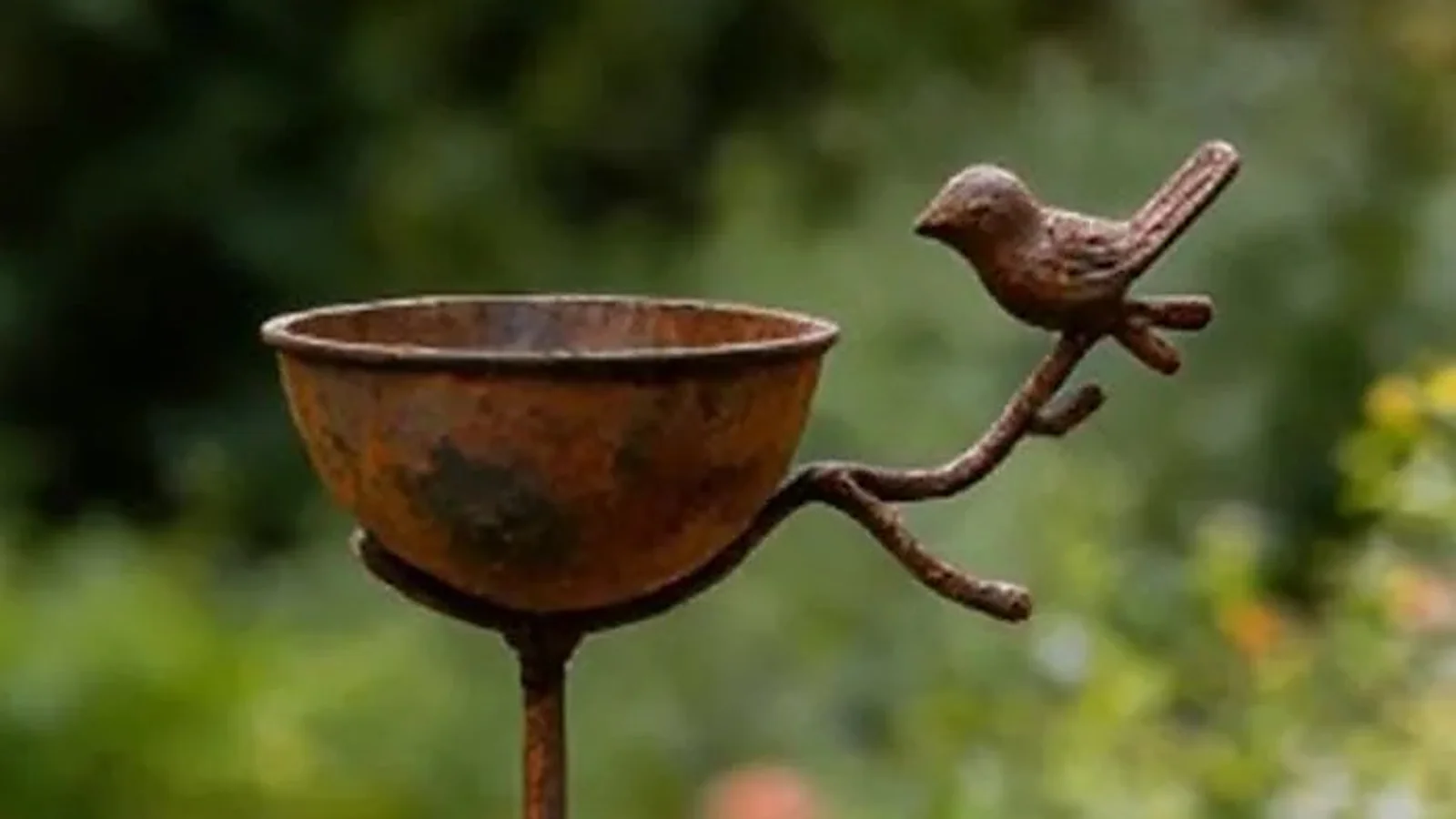 Rustic iron bird bath stake with a cast bird perched on the branch